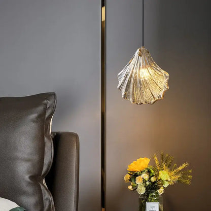 Decorbites led shell pendant light is a translucent ridged glass pendant light with warm golden lighting shaped like a seashell
