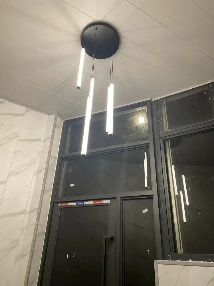 Modern black circular DecorBites™ LED spiral staircase chandelier with three vertical white LED light tubes for home use