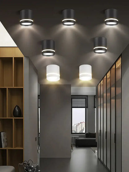 Six matte black cylindrical decorbites led spot ceiling downlights with frosted shades illuminate a modern hallway