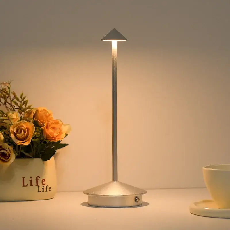 A sleek silver cordless led table lamp with slender pole and triangular light head for ambient room decor