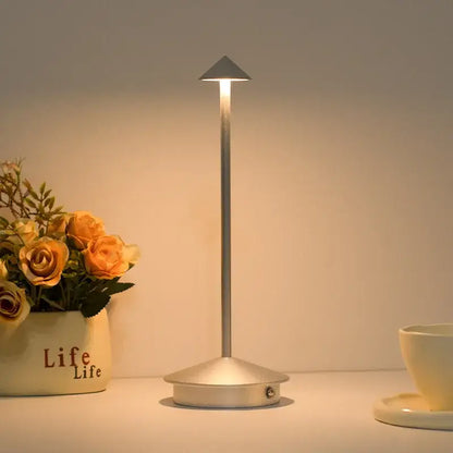 A sleek silver cordless led table lamp with slender pole and triangular light head for ambient room decor