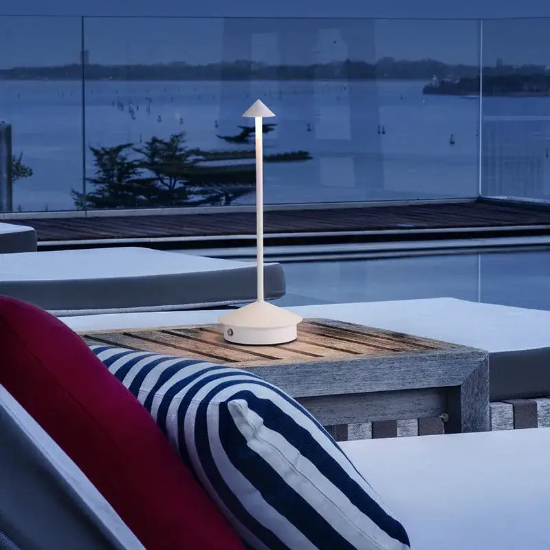 Cream-colored decorbites™ led table lamp with slender stem and conical top on wooden tray for ambient lighting