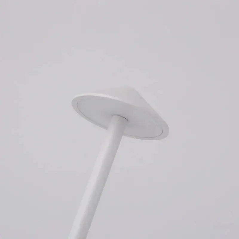 A sleek white cordless led table lamp with a conical shade and cylindrical pole for ambient bedside lighting