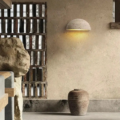 Half-spherical decorbites led travertine wall light with textured concrete finish emits warm natural yellow ambiance light