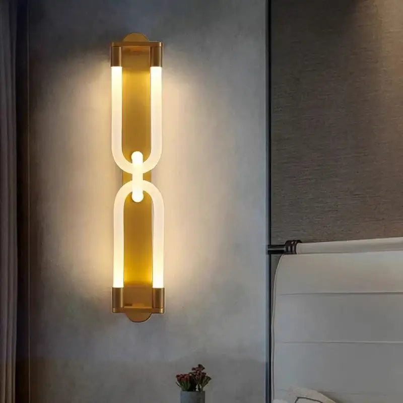 Modern gold-toned decorbites led tube wall sconce with sleek acrylic panels and black metal curved link design