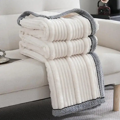 A cream-colored fleece luxury sofa blanket with ribbed texture and gray knitted border from Decorbites light luxury