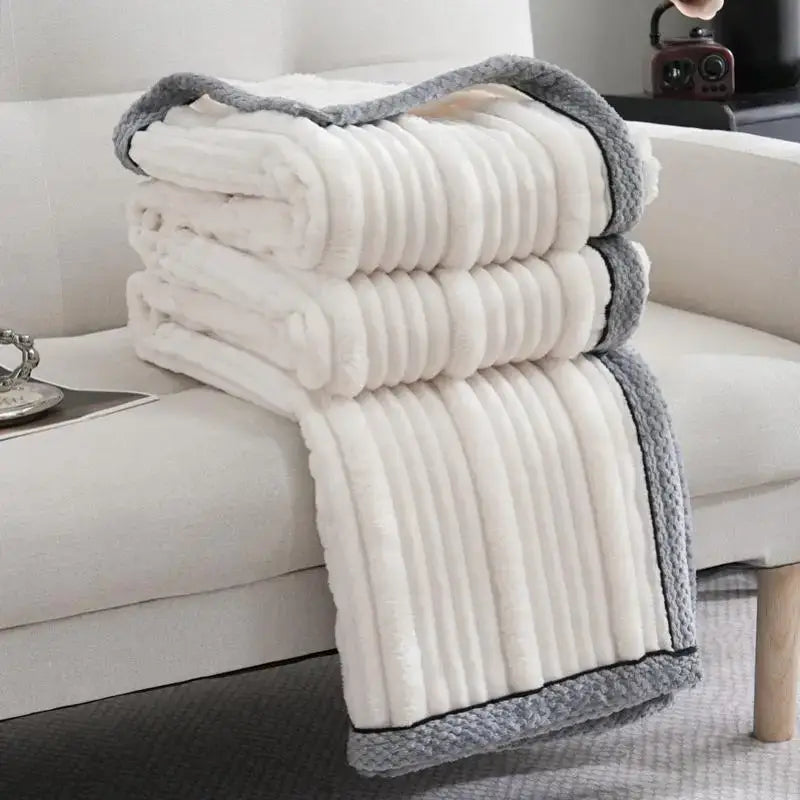 A cream-colored fleece luxury sofa blanket with ribbed texture and gray knitted border from Decorbites light luxury