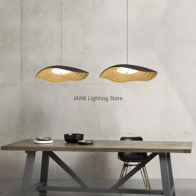 Two modern decorbites lotus leaf chandelier pendant lights with layered wave design in natural wood and black finish hanging above table