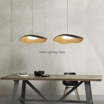 Two modern decorbites lotus leaf chandelier pendant lights with layered wave design in natural wood and black finish hanging above table