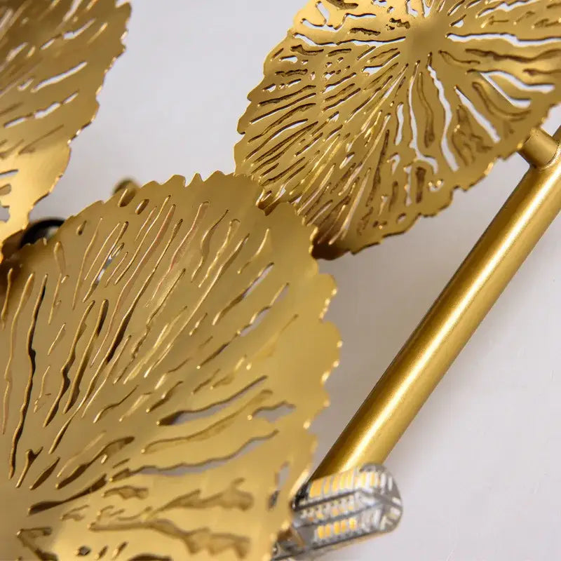 Gold-colored metal decorbites lotus leaf wall lights with intricate cutout patterns and sleek cylindrical arm for living spaces