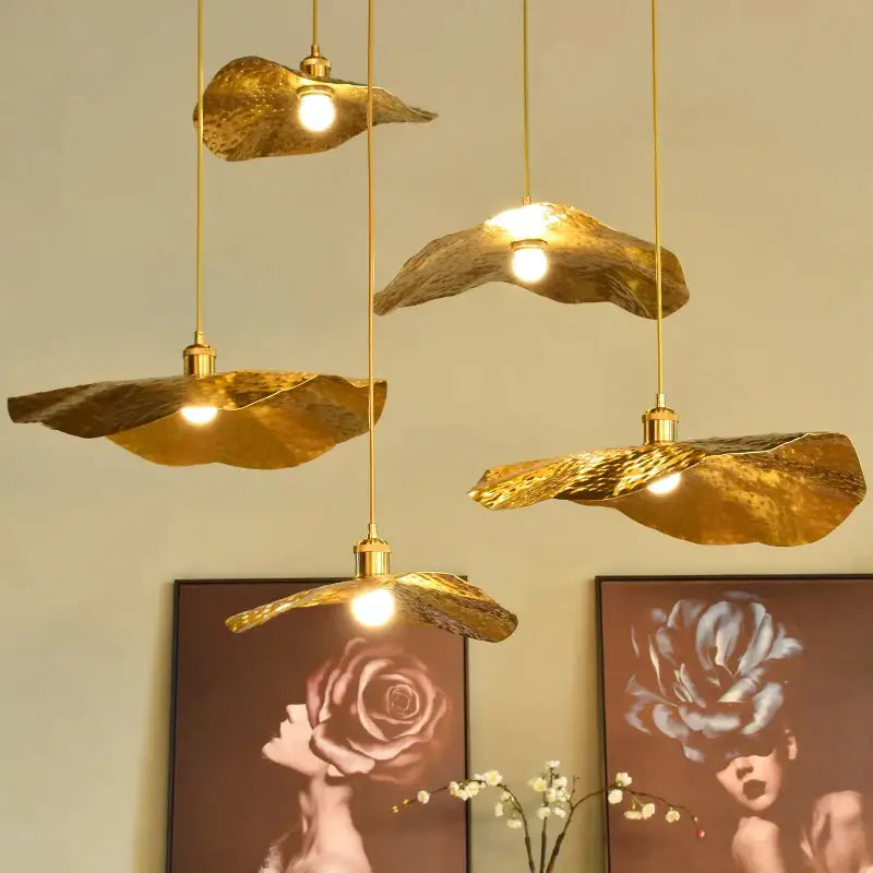 Golden leaf-shaped pendant light with hammered metal finish hang from gold cords in decorbites lotus leaf pendant