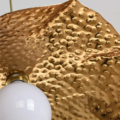 Gold-toned hammered metal pendant light with textured bubbly surface and white bulb from decorbites lotus leaf pendant collection