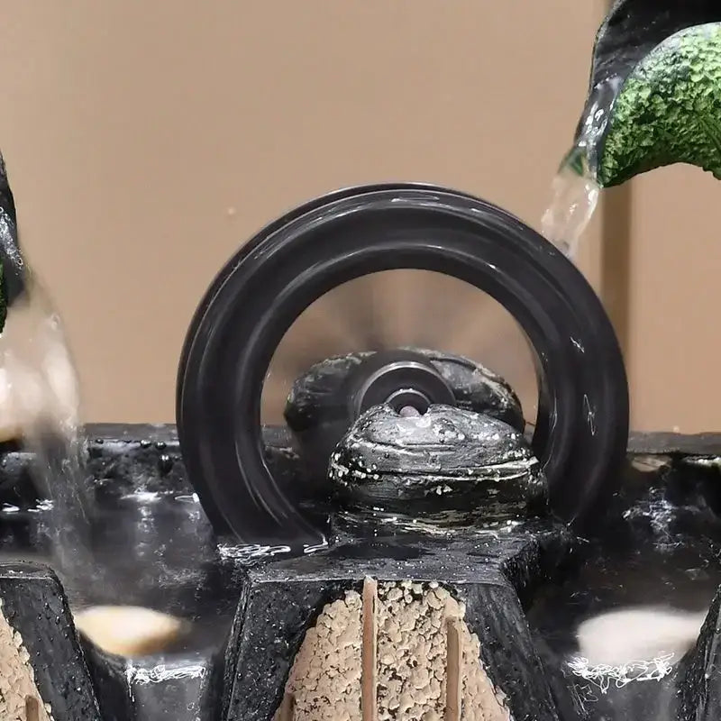 Black circular water wheel with textured surface and central mechanism in decorbites lotus leaf water feature fountain