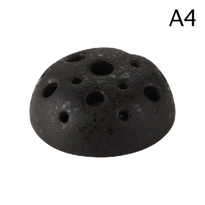 Black textured ceramic vase with multiple circular holes resembling lotus seedpod made from stone sand material