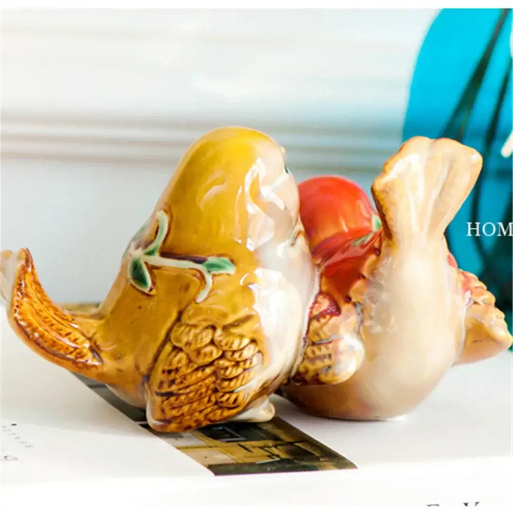 Hand-painted DecorBites love birds porcelain couple ornament featuring yellow and beige birds with leaf and red accents