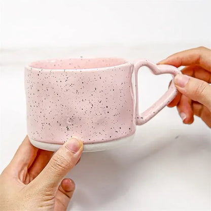 A pink speckled ceramic mug with a heart shaped handle from decorbites love handle ceramic collection for tea and coffee