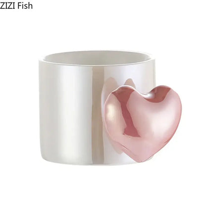 A glossy white ceramic mug with a blush pink love heart ceramic handle for coffee tea or juice by DecorBites™