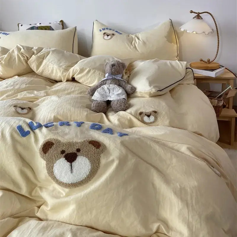 Cream-colored DecorBites™ embroidered bedding set featuring plush teddy bear appliqué and blue lucky day text