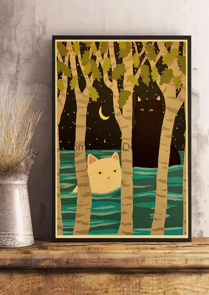 A framed decorated paper poster featuring two cats in light yellow and black among stylized trees and a crescent moon