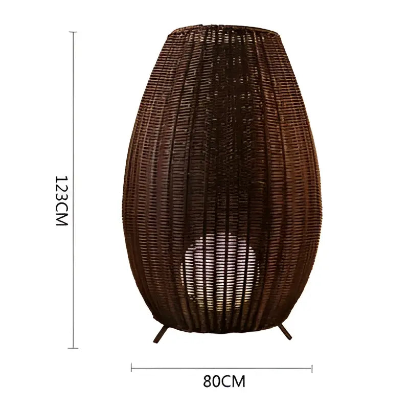 Brown woven wicker floor lamp with tapered teardrop shape and black metal legs for decorbites lucide colin rattan use