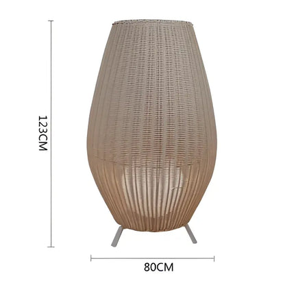 Beige woven rattan floor lamp with tapered vase shape and three metal legs decorbites lucide colin rattan design