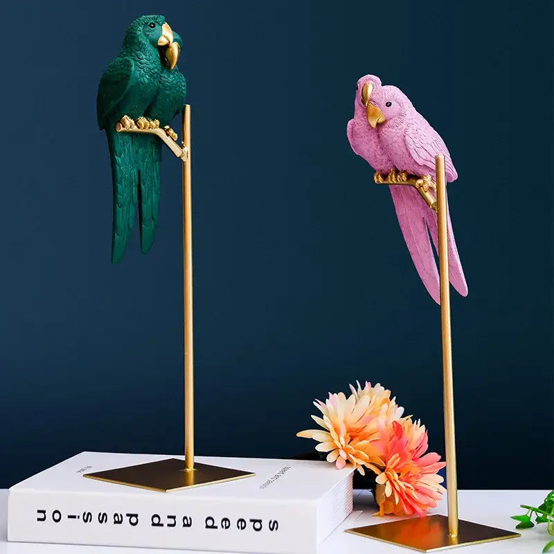 Two decorative decorbites lucky parrot resin ornaments in emerald green and soft pink on gold stands for modern home decor
