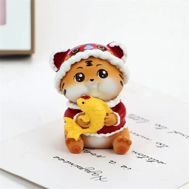 Cute orange tiger figurine wearing red and white santa hat holding yellow fish decorbites lucky tiger figurine