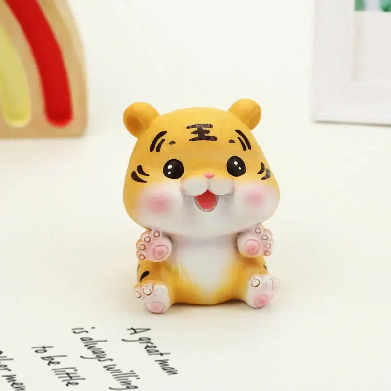 Cute yellow lucky tiger figurine with black whisker markings and pink cheeks sitting on a white surface by decorbites