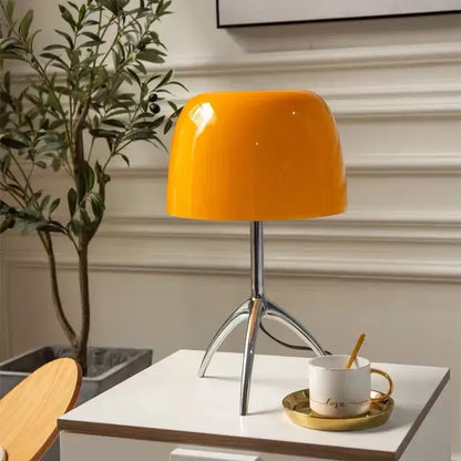 Vibrant orange glossy ceramic decorbites lumiere table lamp with sleek chrome tripod base for modern bedroom use
