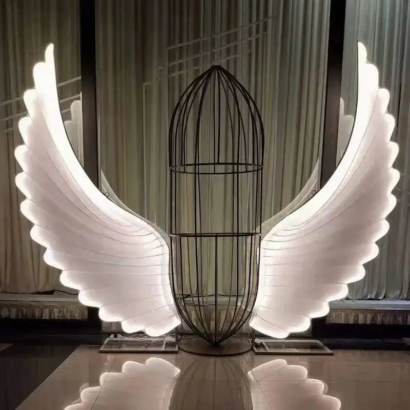 A glowing white led angel wings sculpture with a black wire cage body by decorbites luminescent angel wings lamp
