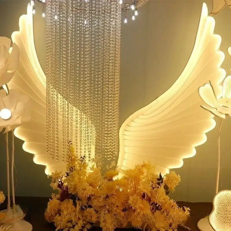 Illuminated white angel wings with a cascading crystal chandelier in the decorbites luminescent angel wings lamp for parties