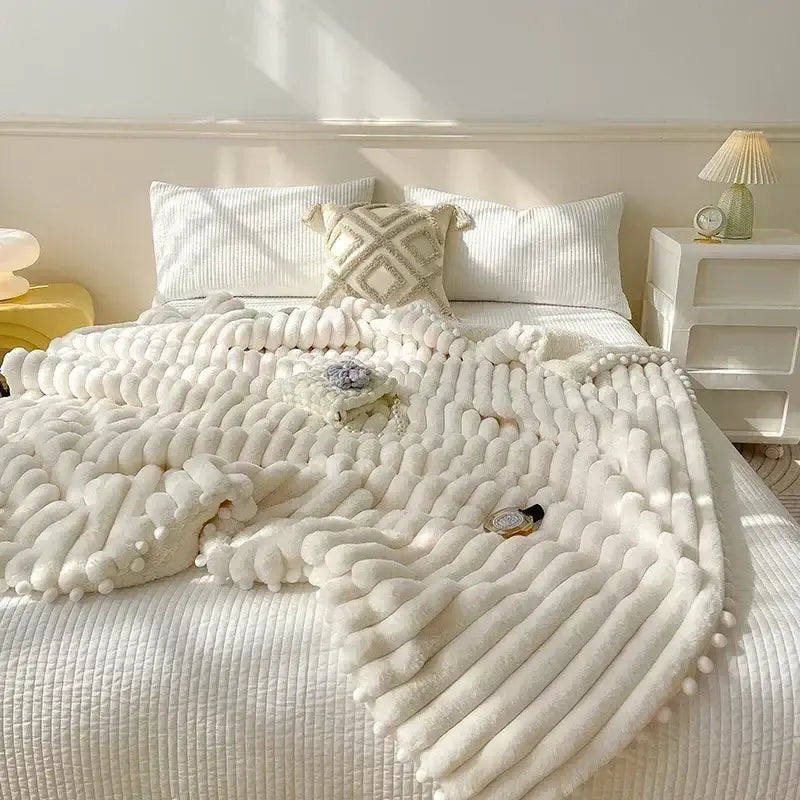 Cream-colored plush knit throw blanket with ribbed pattern and pom-poms featuring faux rabbit fur for cozy bed warmth