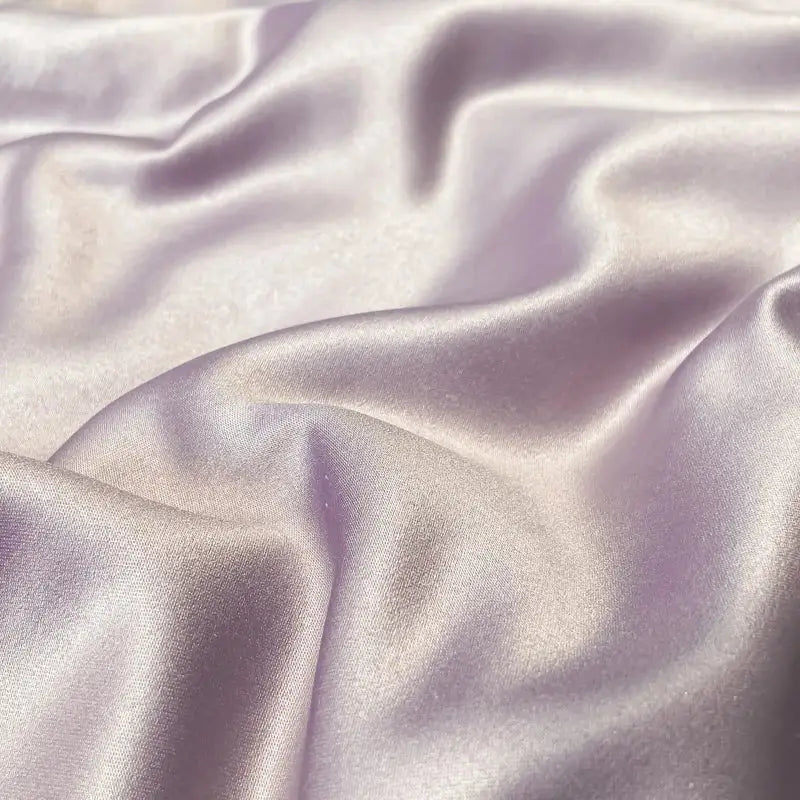 A soft lavender satin fabric with smooth glossy folds in the DecorBites Luxe Flower embroidered quilt set