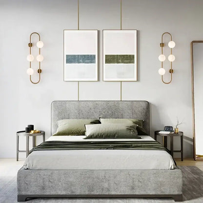 Gray upholstered bed with diamond patterned headboard and footboard showcased alongside decorbites luxe glass ball led wall sconce
