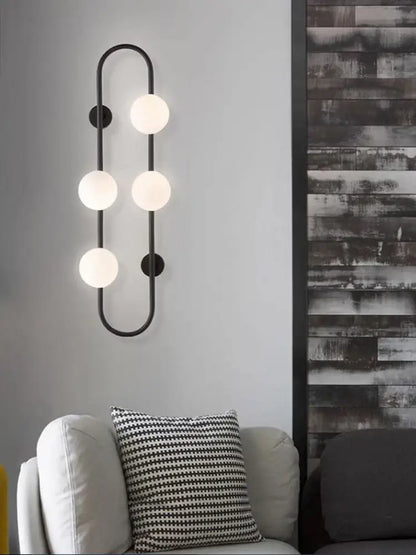 Black metal wall sconce with five frosted globe bulbs in a curved design for modern bedroom by decorbites luxe glass