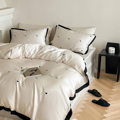 Cream-colored 100% lyocell bedding set featuring luxe heart embroidered duvet cover with black heart embroidery and trim