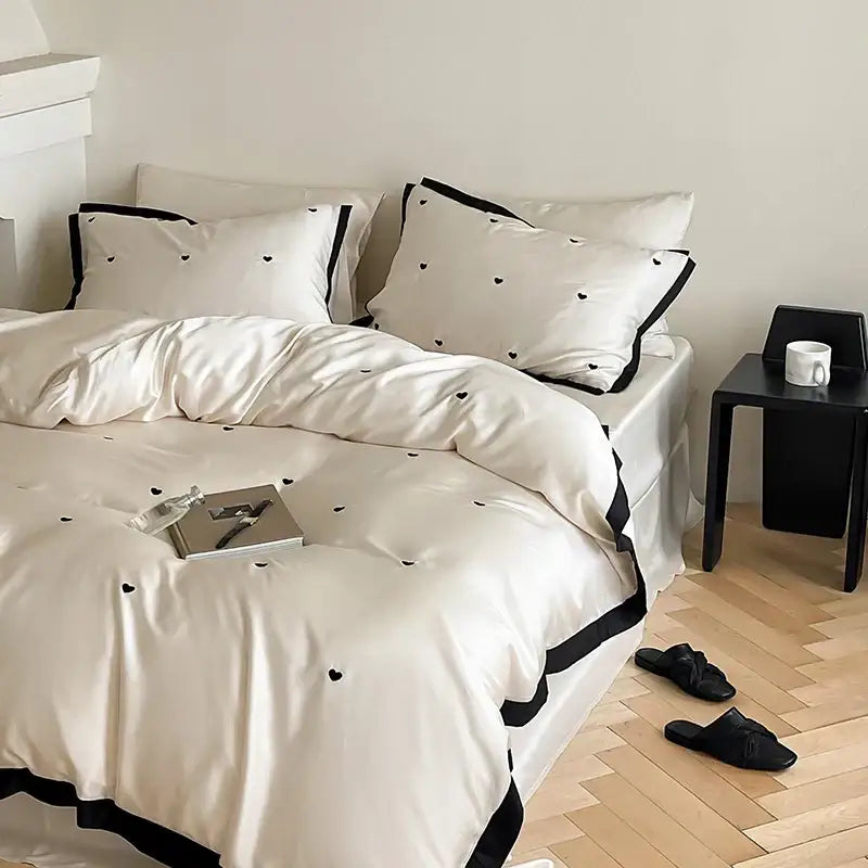 Cream-colored 100% lyocell bedding set featuring luxe heart embroidered duvet cover with black heart embroidery and trim