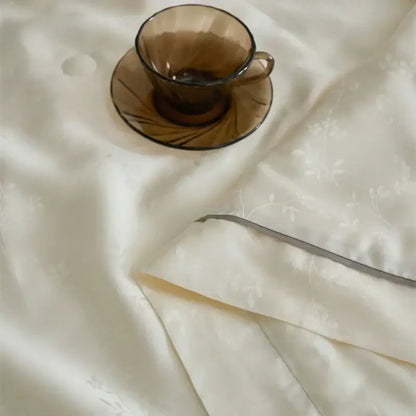 A translucent amber glass teacup with radial etching on a decorbites luxe lyocell summer blanket with mulberry silk fill