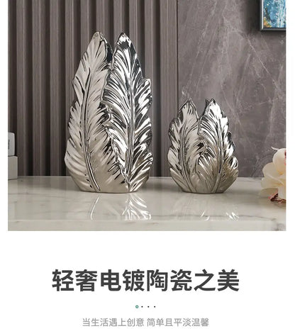 Two silver electroplated ceramic leaf sculptures with detailed veining complement luxurious gold ceramic vases for home decor