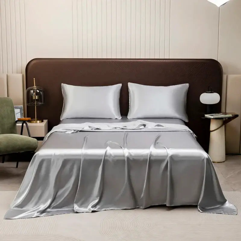 Silver satin bedding set with solid color flat sheet and matching pillowcases elegantly draped on modern bed