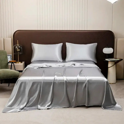 Silver satin bedding set with solid color flat sheet and matching pillowcases elegantly draped on modern bed