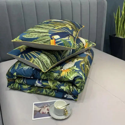 Stacked tropical-themed cotton duvet cover set with vibrant toucan and leaf patterns on deep blue fabric and matching pillowcases