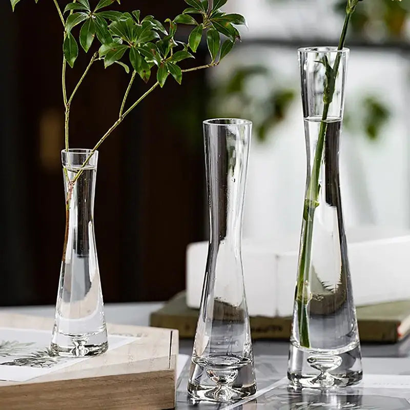 Three clear glass flower vases with slender necks and ornate footed bases for luxury home decor by DecorBites luxury glass vase