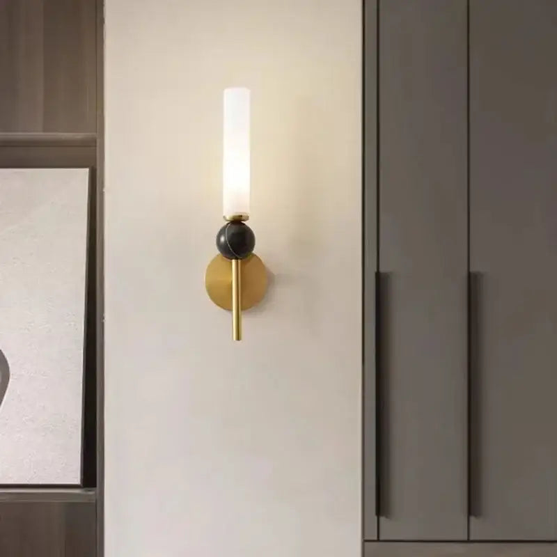 Gold-toned decorbites marble sconce wall light with frosted glass cylinder and black spherical accent