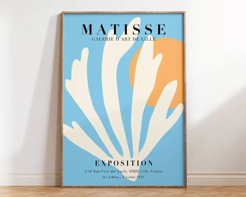A framed DecorBites™ matisse floral print featuring white coral on light blue with an orange circle and exhibition text
