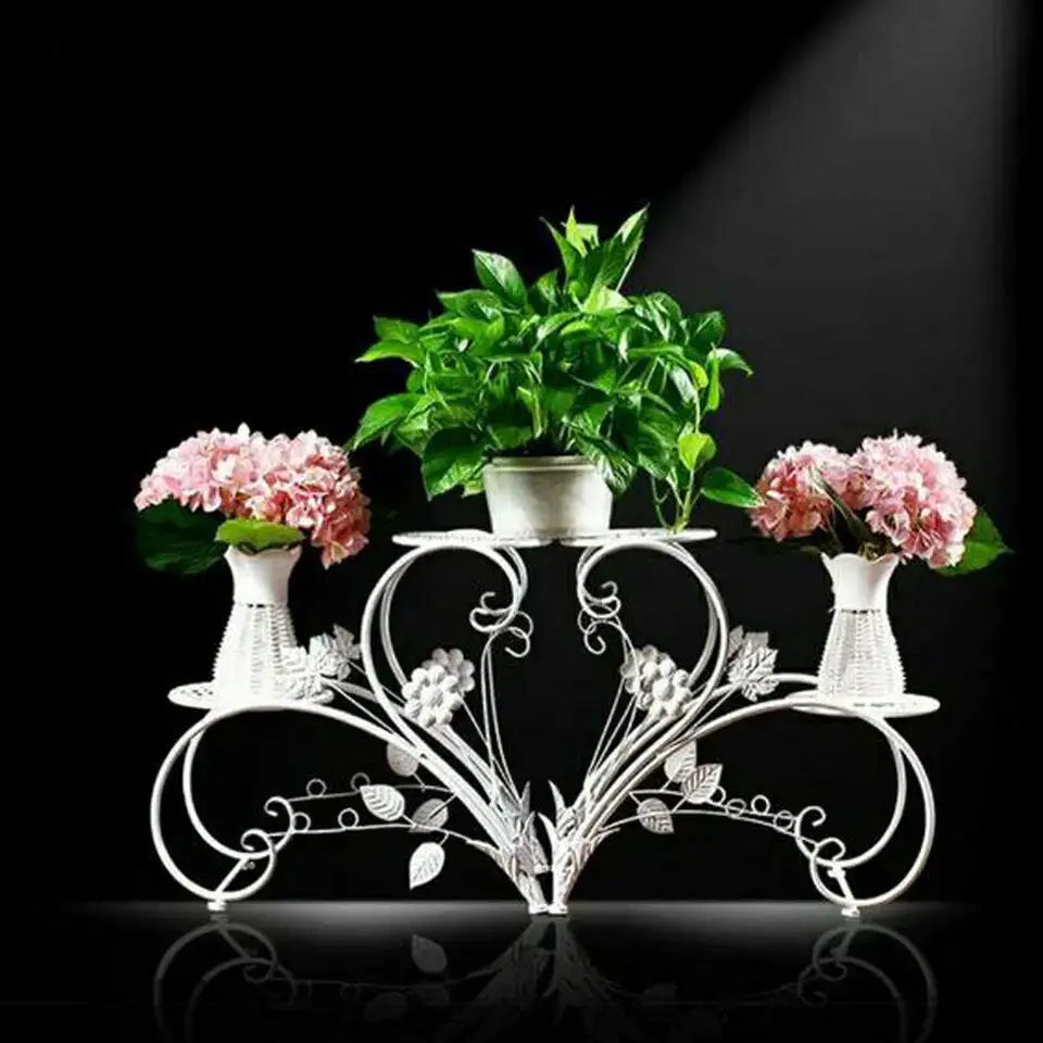 White wrought iron metal plant stand set by DecorBites with ornate floral design and three tiers for four potted plants