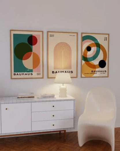 Set of three framed bauhaus-style mid century modern posters with geometric designs in muted teal orange and cream tones