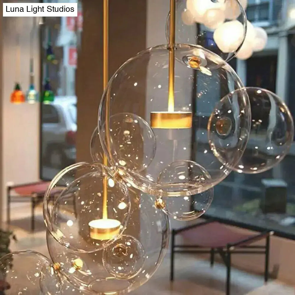 DecorBites™ minimal brass bubble pendant light with five clear glass heads and warm LED bulbs in modern design