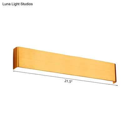 A sleek brushed gold rectangular wall lamp with modern design and warm white light for living room use