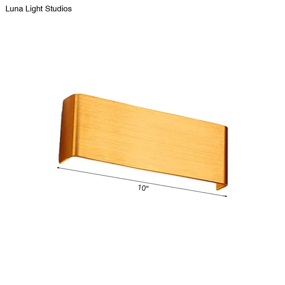A sleek brushed gold rectangular wall lamp with minimalist design providing warm white light for living room use